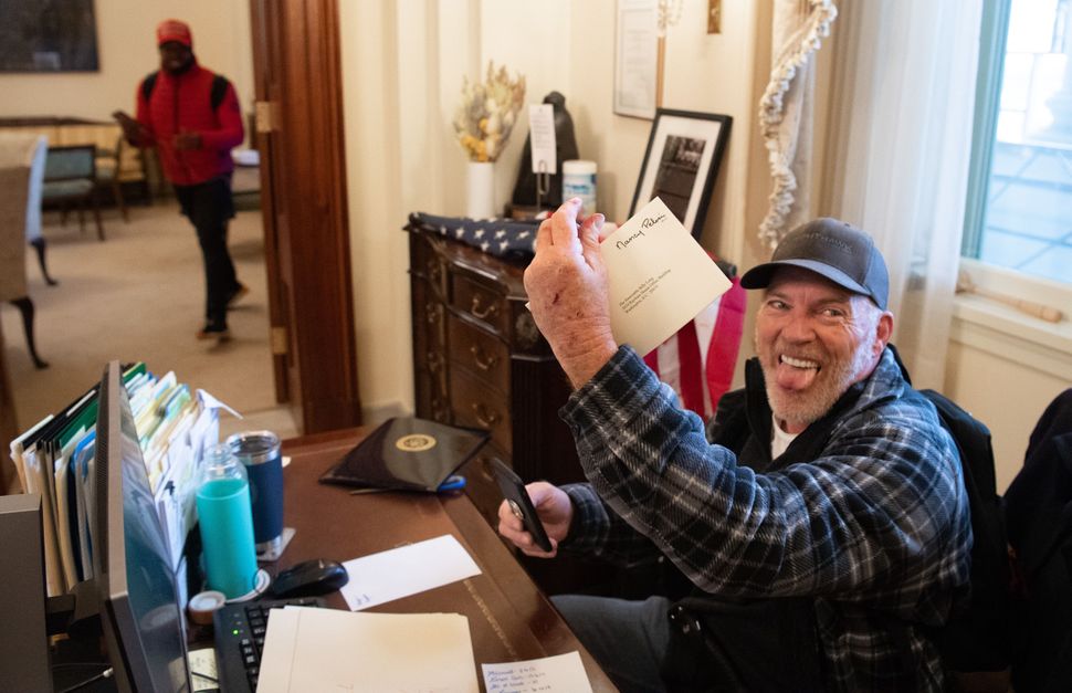 Richard Barnett, a supporter of President Donald Trump, holds a piece of mail as he sits inside the office of House Speaker N