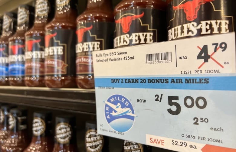 A row of Bull's Eye BBQ Sauce is flanked by a "buy 2 earn 20 bonus Air Miles" sign at a Calgary Safeway.
