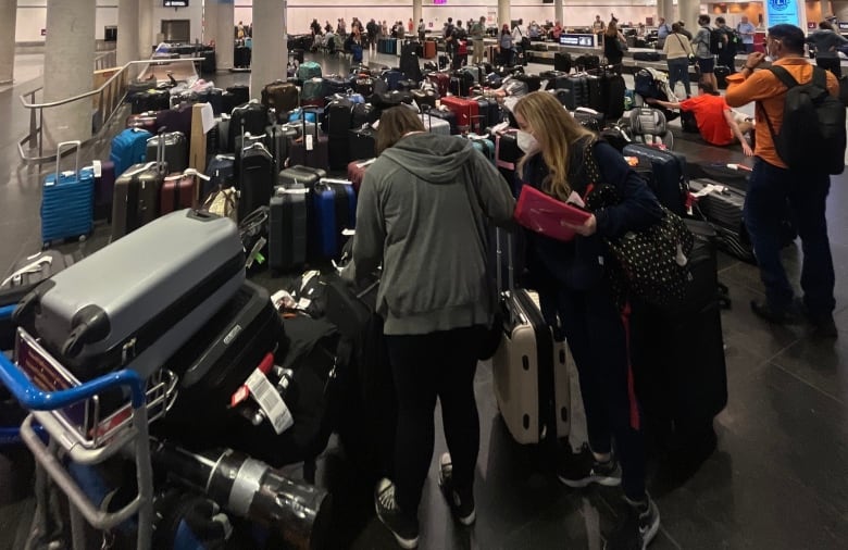 Travellers are seen amid unclaimed luggage at an airport. 