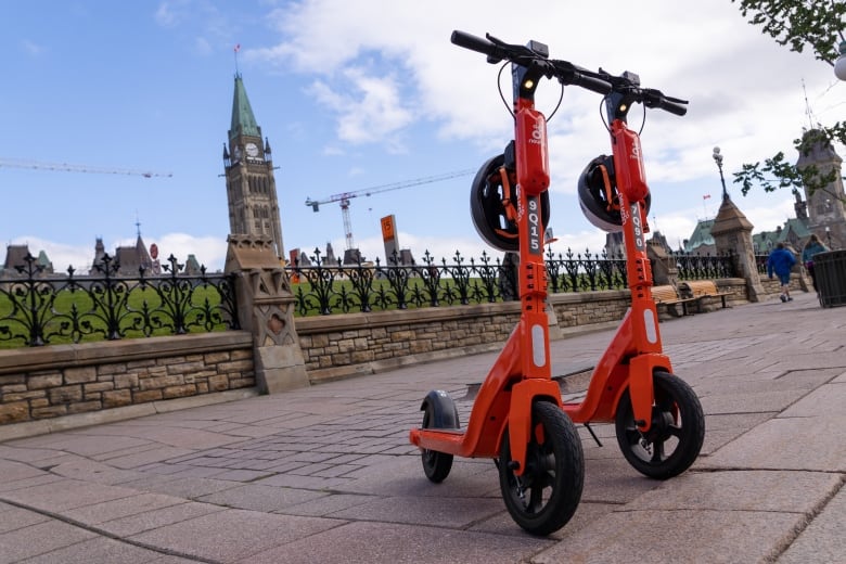 Two e-scooters with Parliament Hill in the background.