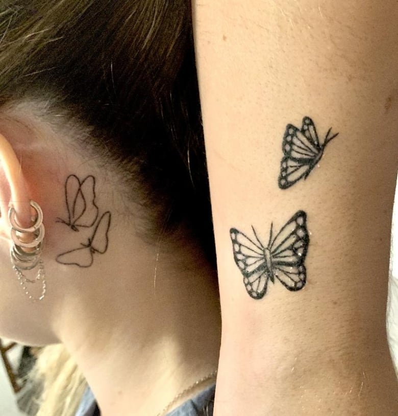 A close up of two matching tattoos of two butterflies. On the left is the tattoo behind a woman's ear, on the left is a similar tattoo with more detail on the inside of a woman's wrist.