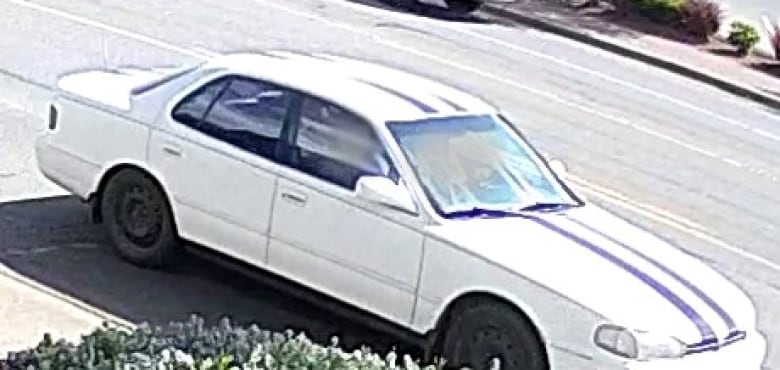A white sedan car with black racing stripes painted vertically over the hood and roof.