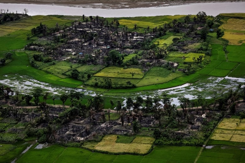An aerial view of burned structures surrounded by green, grassy fields.