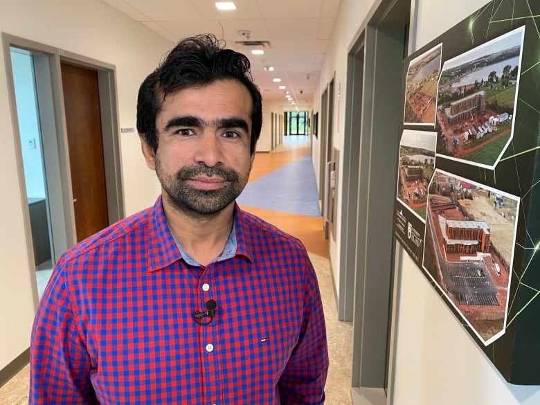 Picture shows Dr. Aitazaz Farooque standing in the hallway of the UPEI Canadian Centre for Climate Change and Adaptation. On the right wall there are pictures of the centre in development. 