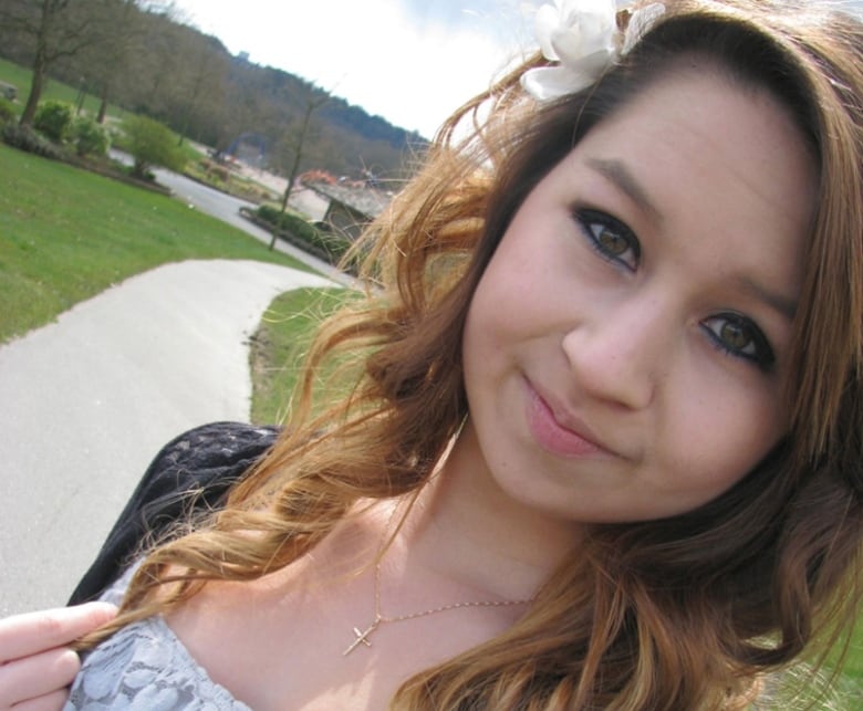 Amanda Todd smiles in a selfie. She is wearing a gold cross and a white top.