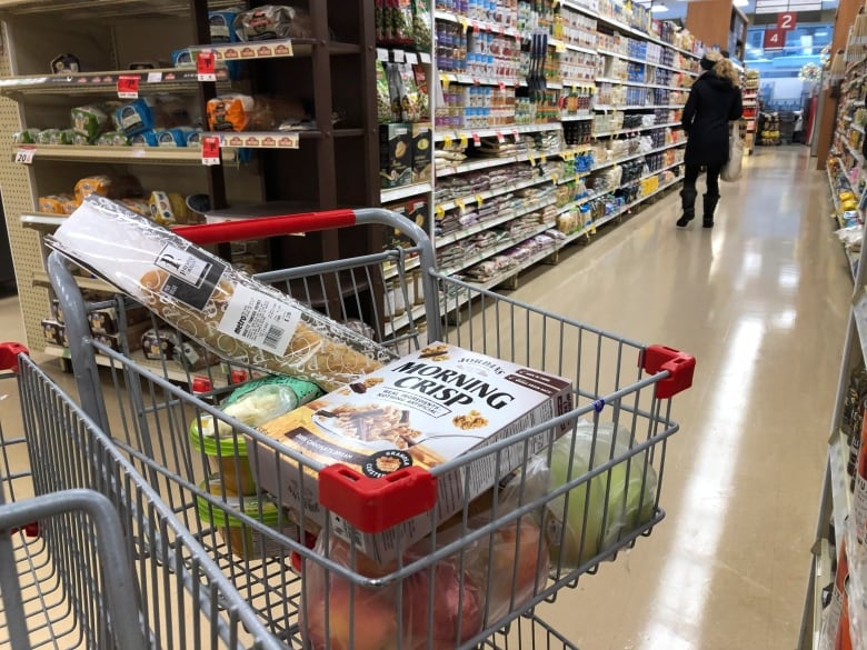 A grocery store shopping cart holding various food items. 