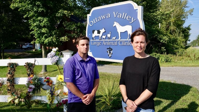 A blue sign reads Ottawa Valley Large Animal Clinic. A man and woman stand in front of it, looking serious.