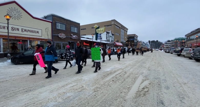 People march down a snowy street holding signs 