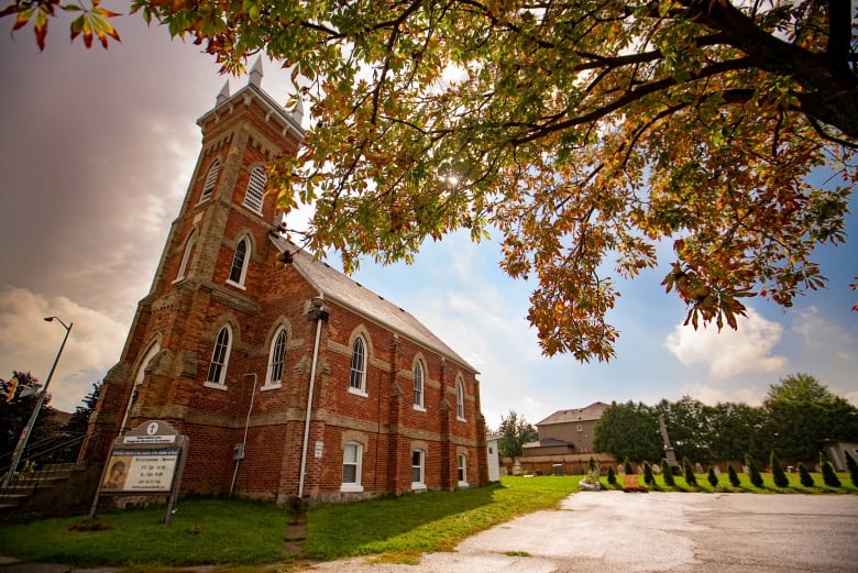 A red-brick church is seen against partly cloudy skies. 