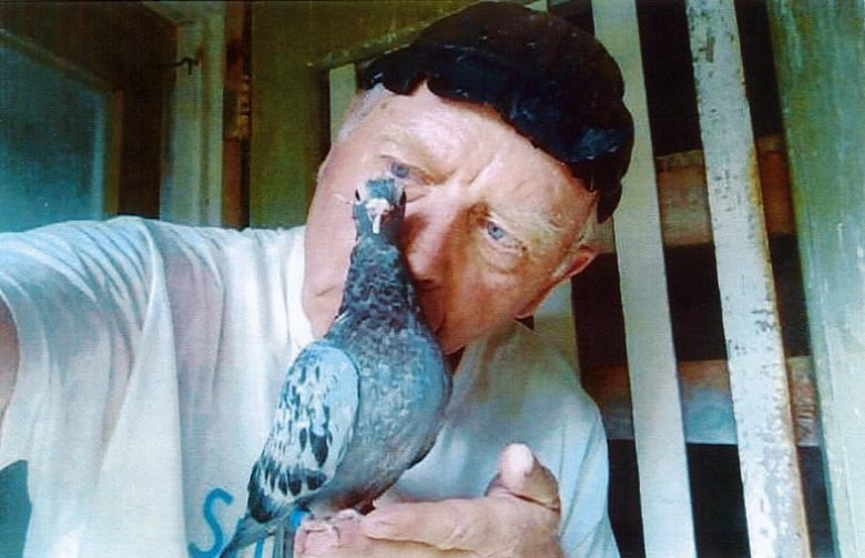 Plasschaert poses with a pigeon in front of his face. 