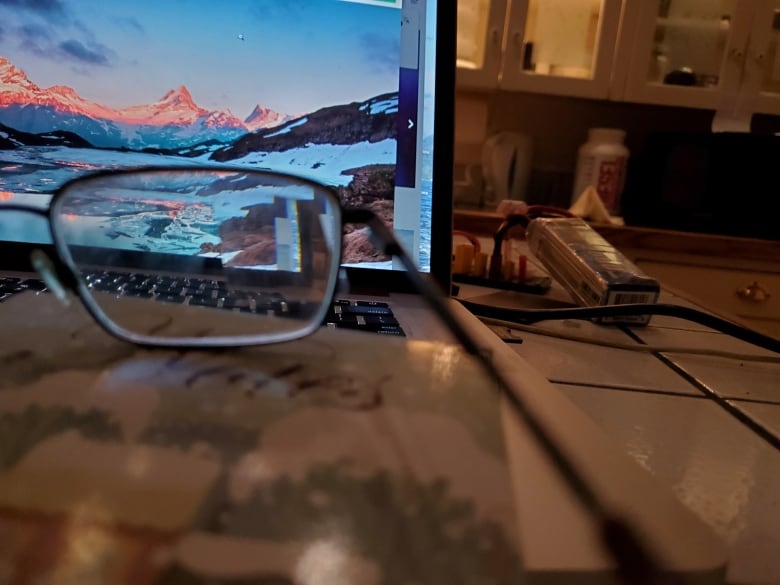 A pair of glasses sit on a laptop. 