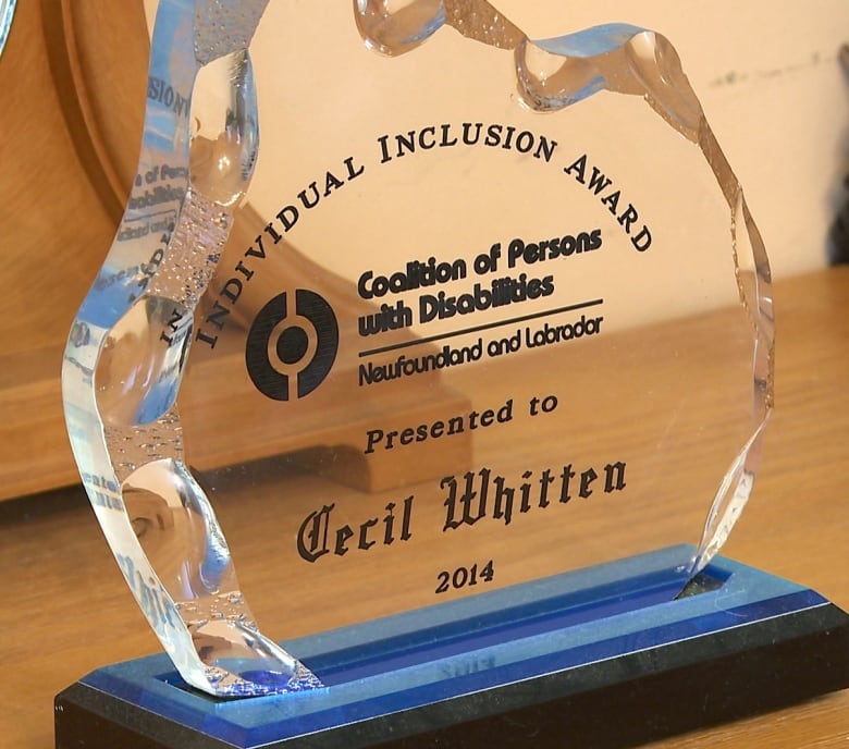 The photo shows an award made of glass. It reads "Individual Inclusion Award. Coalition of Persons with Disabilities Newfoundland and Labrador. Presented to Cecil Whitten, 2014."