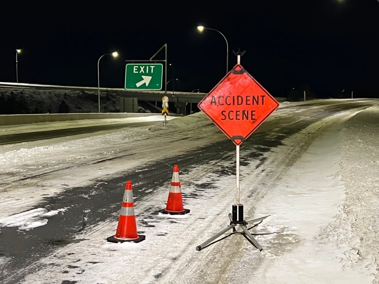 A snowy highway exit, with orange traffic cones and a sign that reads 'ACCIDENT SCENE'. A green 'EXIT' sign is visible in the background.