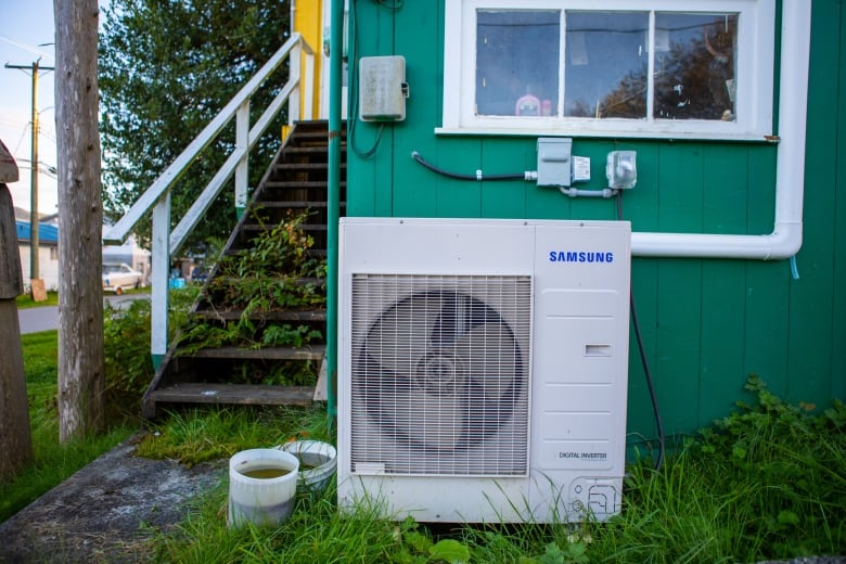A squat air-conditioner-like box sits outside a home.