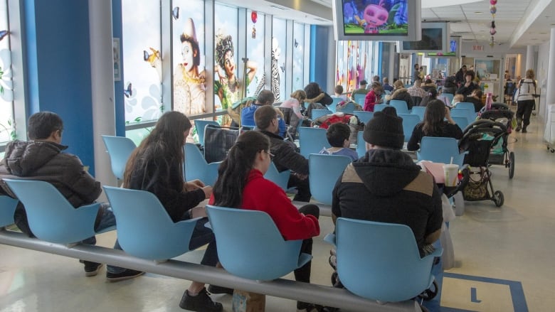 Les gens sont assis sur des chaises dans une salle d'attente d'hôpital.