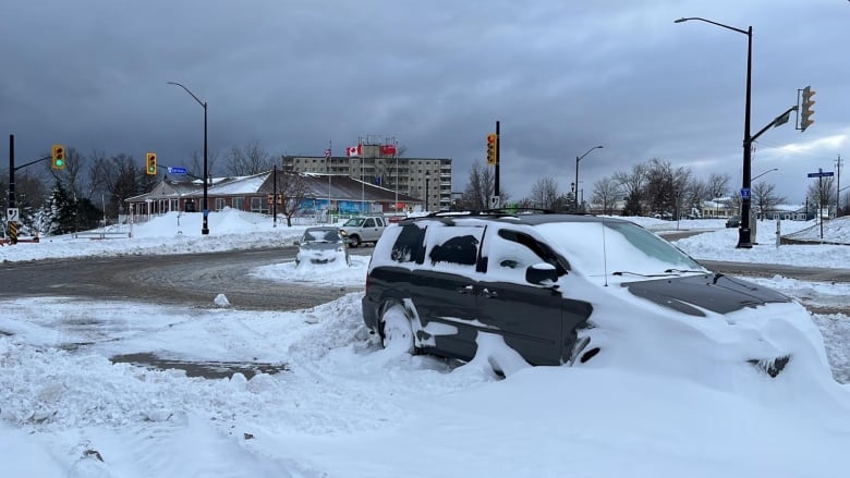 Un véhicule en stationnement recouvert de neige. 