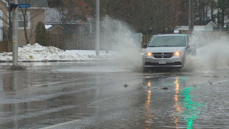 Une camionnette traverse de grandes flaques d'eau dans une rue.