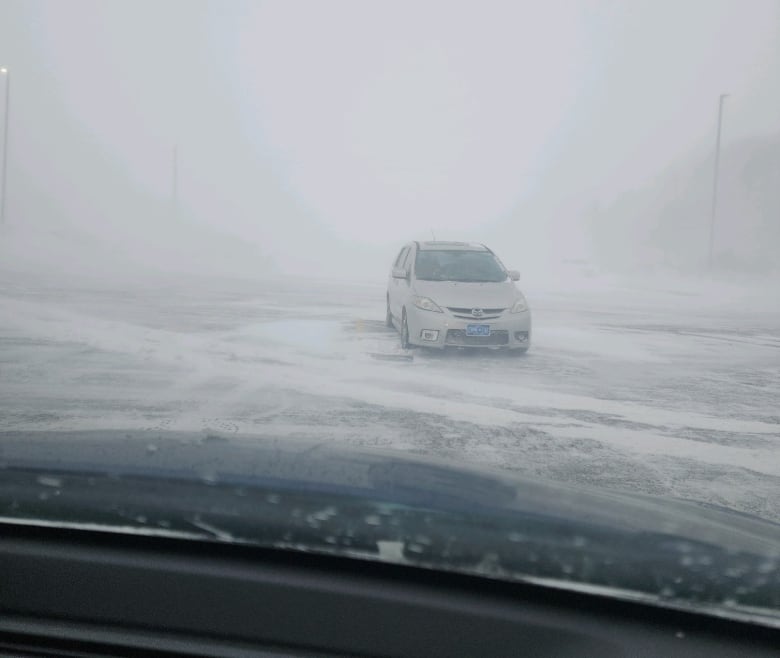 A vehicle is parked in a parking lot in heavy snow