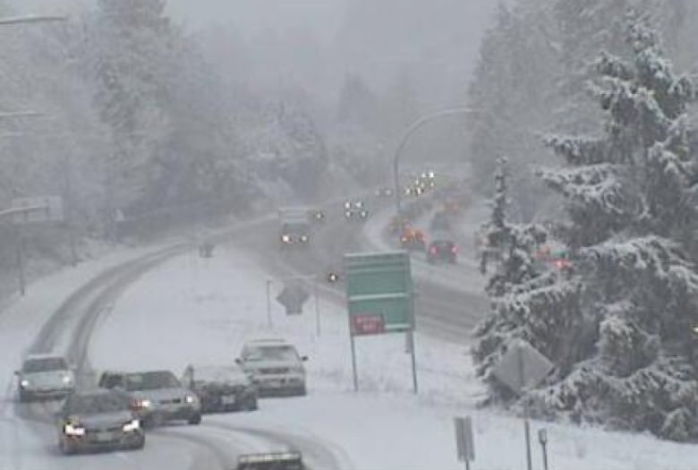 A webcam shows a significant amount of snowfall and piled up cars at a highway exit.