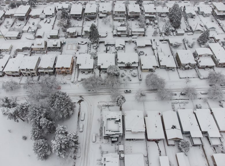 An aerial view of a car driving past a row of snow-covered houses in Vancouver.
