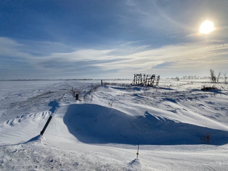 A field covered in snow drifts on a sunny winter day.