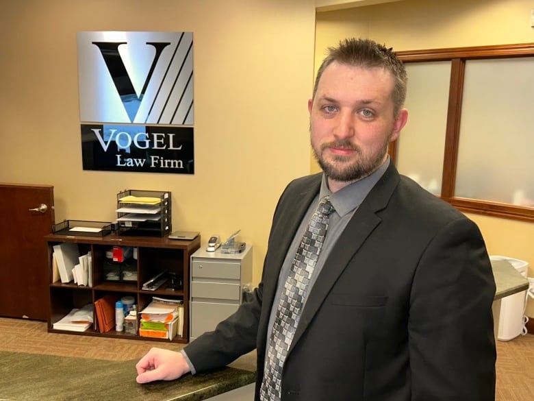 A man in a suit poses in a law firm office.