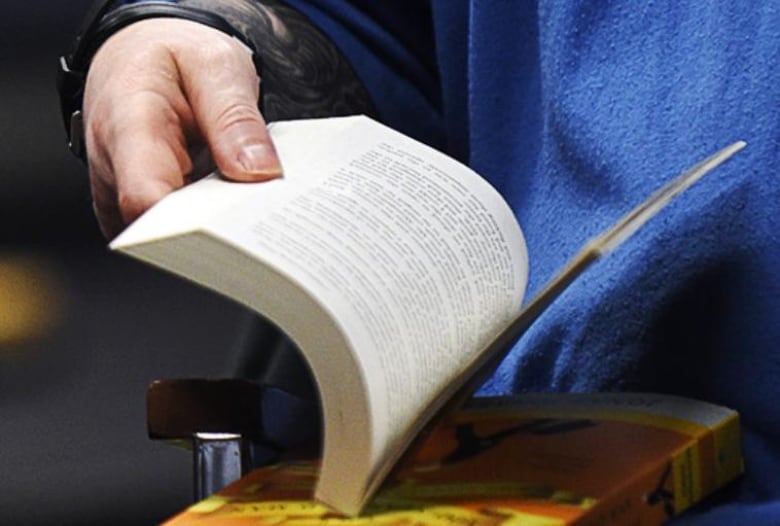 A person flips through a book at the bookclubs for inmates