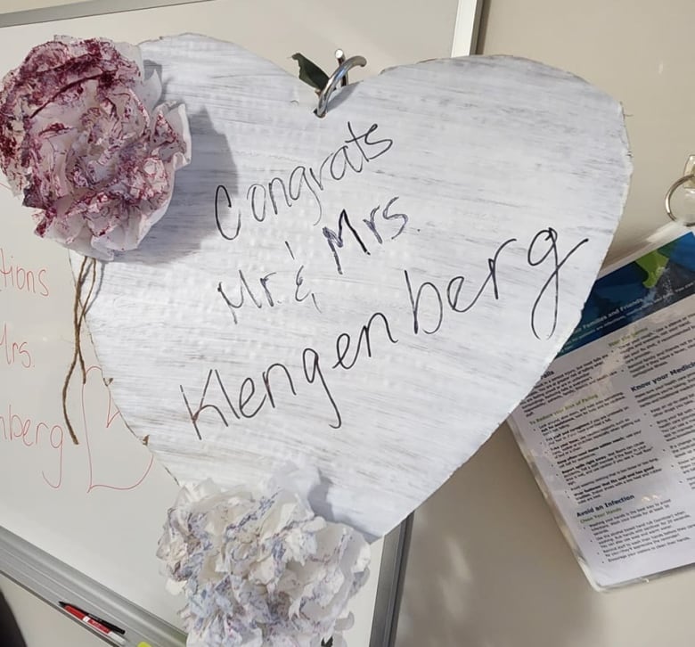 A paper heart, decorated with flowers, is posted on a whiteboard and reads, 'Congrats Mr. and Mrs. Klengenberg.'