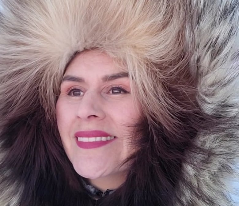 An Indigenous woman wears a parka with a fur trimmed hood. 