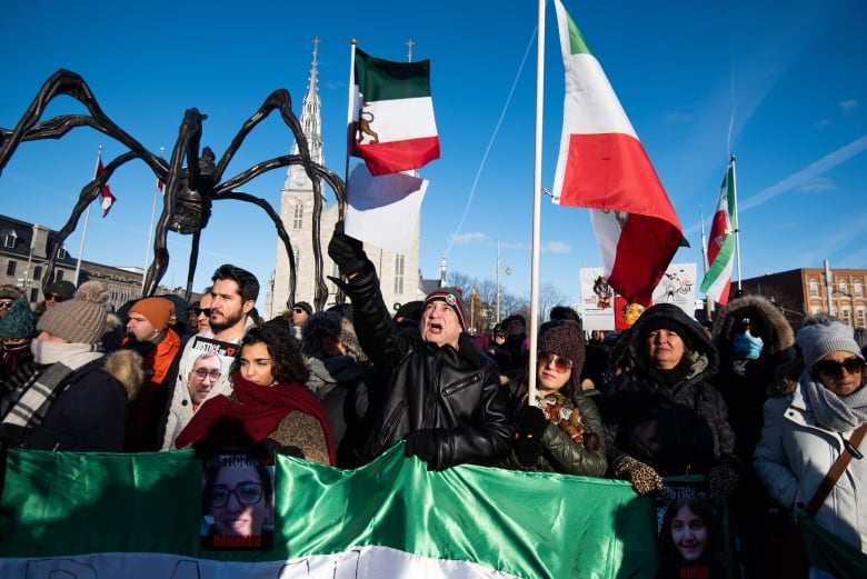 A crowd of people wave red, white and green flags during an outdoor rally in winter.