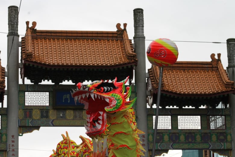 A Chinese dragon is pictured, with a large Chinatown gate in the background.