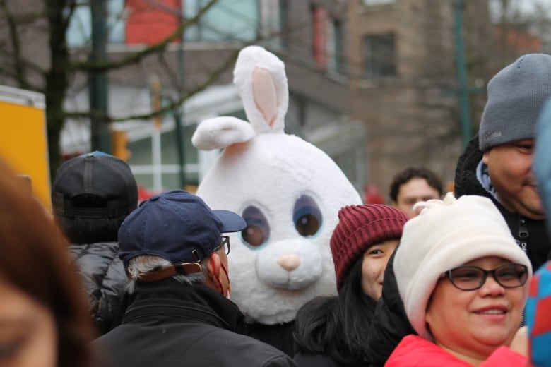 A person in a rabbit fursuit is pictured at a parade.