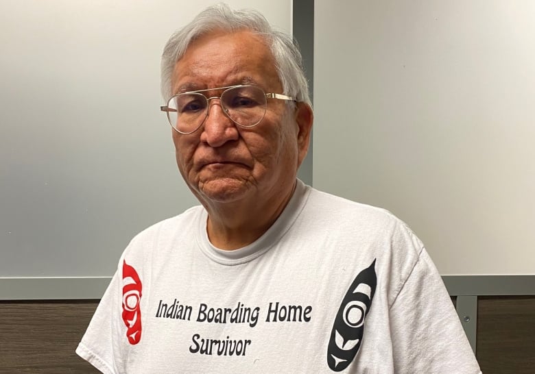 A man in a white shirt that says "Indian boarding home survivor."