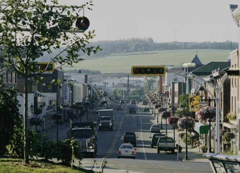 View downhill of small town main street, with landscape in background.