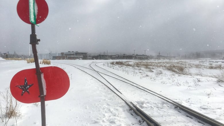 A snowy scene, railway tracks and in the background, a town.