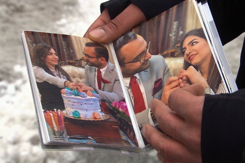 Hand holding photo album with photos of man and woman