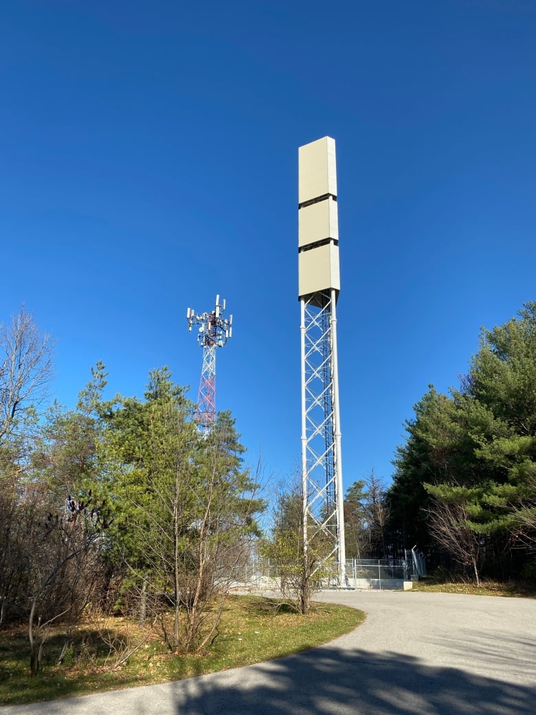 Two tall cell phone towers are shown in close proximity to each other. 