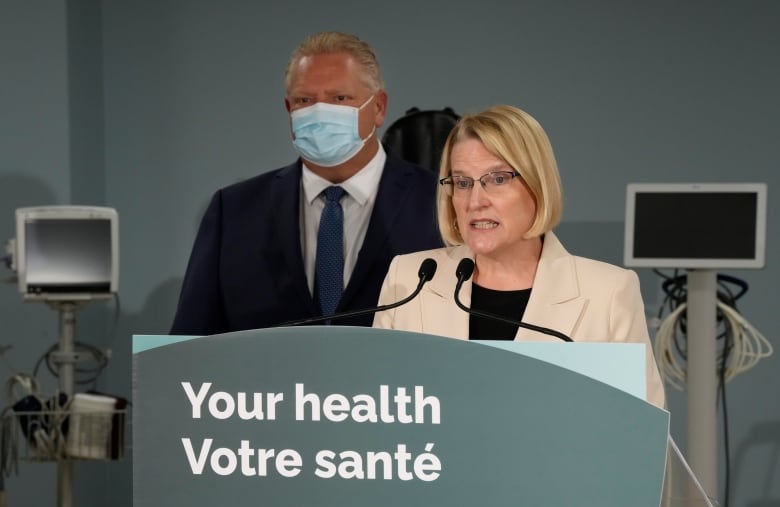 Ontario Health Minister Sylvia Jones makes an announcement in Toronto while Premier Doug Ford stands behind her in the background.
