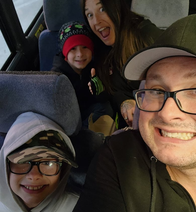 A family of four poses for a selfie on the bus.
