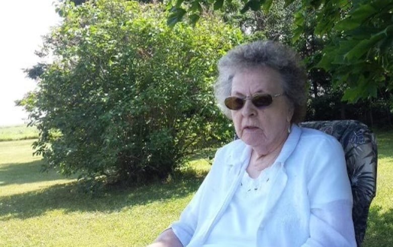 Helena Mullin sits outside at the cottage in a white shirt and sunglasses. 