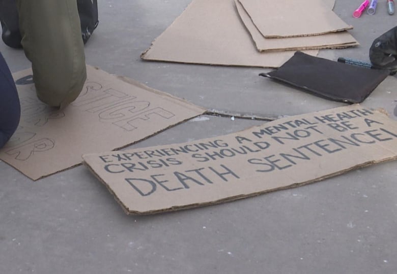 cardboard on the ground. one of the pieces reads 'experiencing a mental health crisis should not be a death sentence' 
