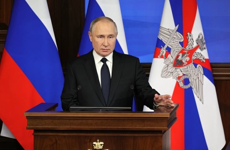 Russian President Vladimir Putin stands at a podium to deliver a speech. 
