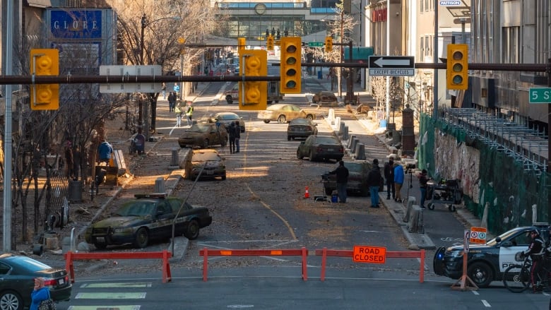 A film set is pictured in downtown Calgary with road closures and abandoned cars.