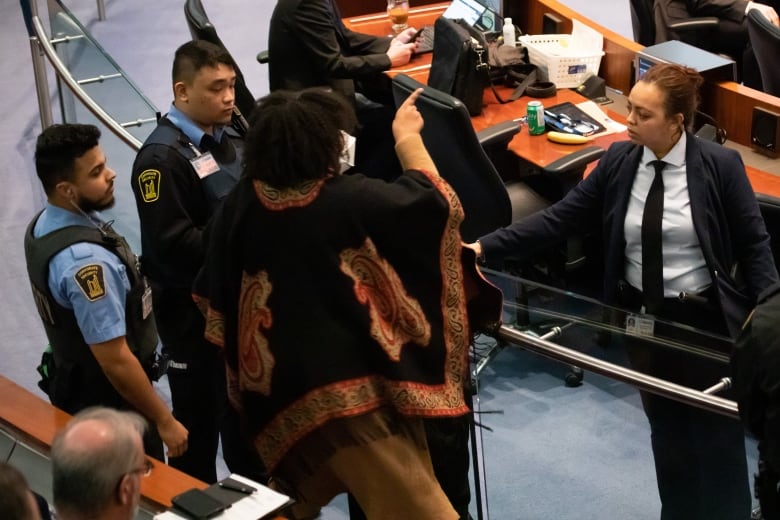 A spectator is escorted out of council chambers during a budget meeting at Toronto City Hall on Feb. 15.