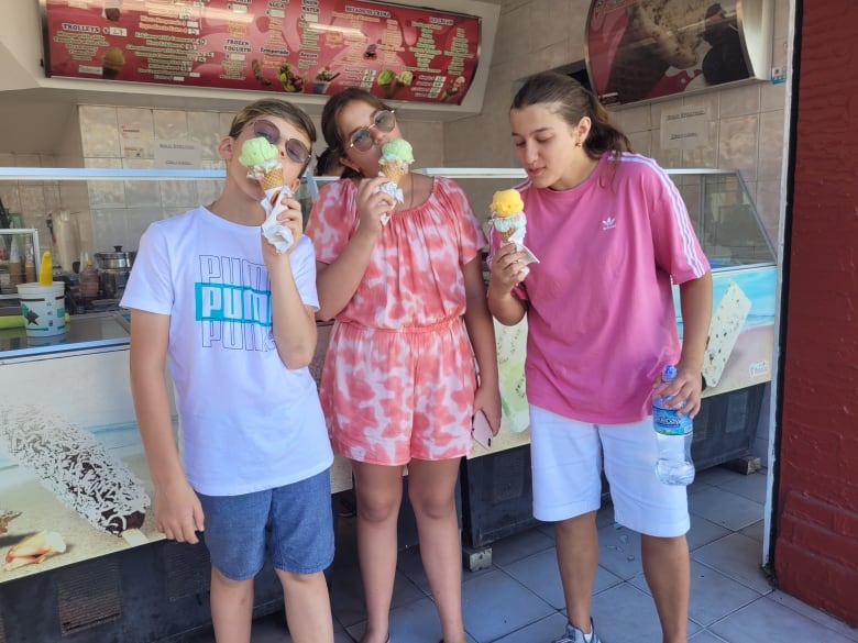 The three children - Maksym, Yuliia and Anastasiia - eat ice cream in a supplied photo from Olga Ostapiv.