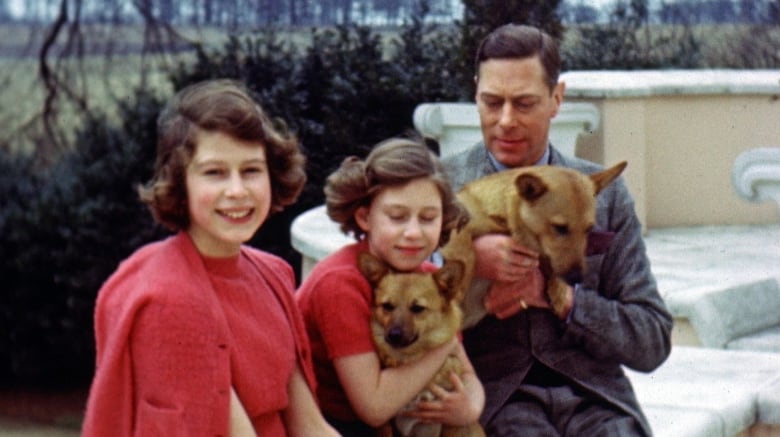 A man and two girls pose for a photo with two dogs.