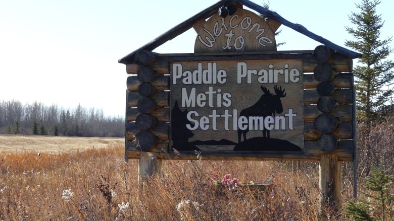 A large wooden sign beside a highway, with the words Welcome to Paddle Prairie Métis Settlement.