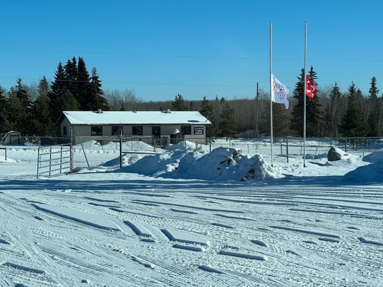 A small building in winter, with two flags at half-mast.