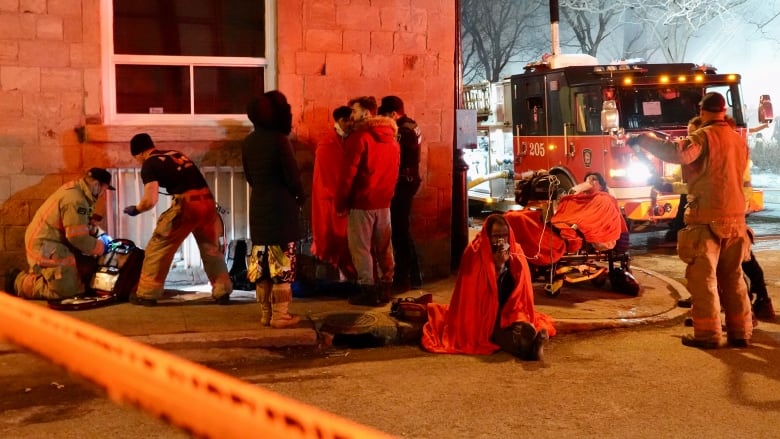 Emergency crews tending to residents on the street, some of whom are using oxygen masks and are wrapped in blankets. 