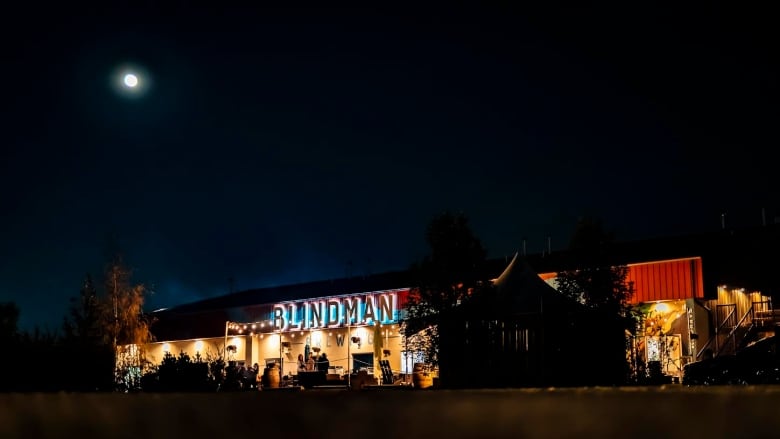 a shot of a lit up building surrounded by a dark night sky. the words blindman are illuminated in blue 
